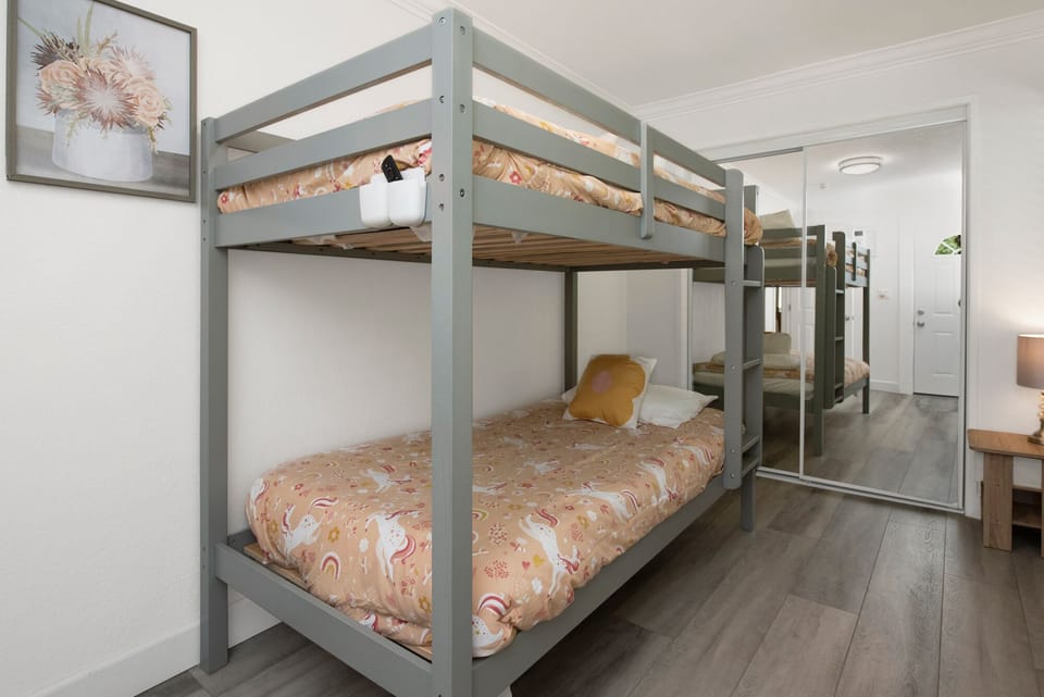 A playful bunk bedroom featuring sturdy twin-over-twin beds with cozy bedding and built-in ladders. Ideal for kids or groups, the space combines comfort and practicality with cheerful décor and smart storage.