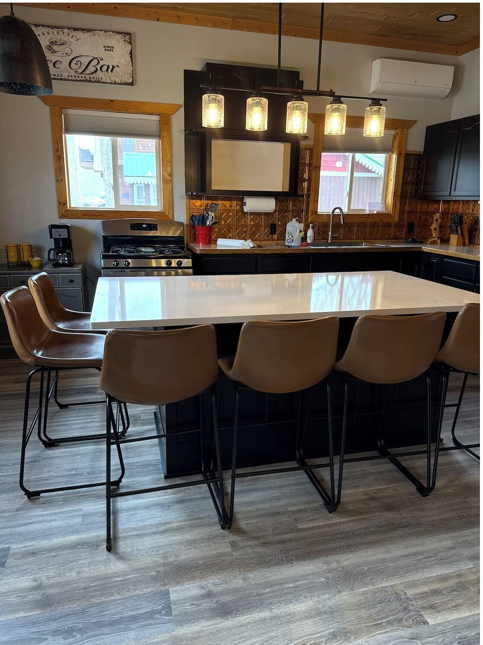 Renovated kitchen with gas range, island seating for 6, and copper backsplash