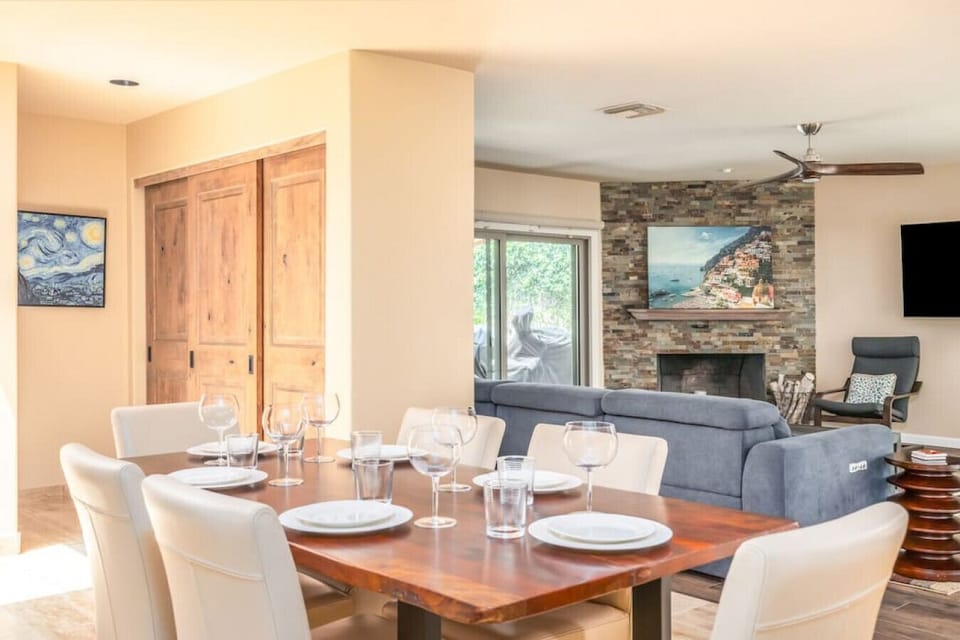 Open dining and living area with warm wood doors and a cozy stone fireplace.