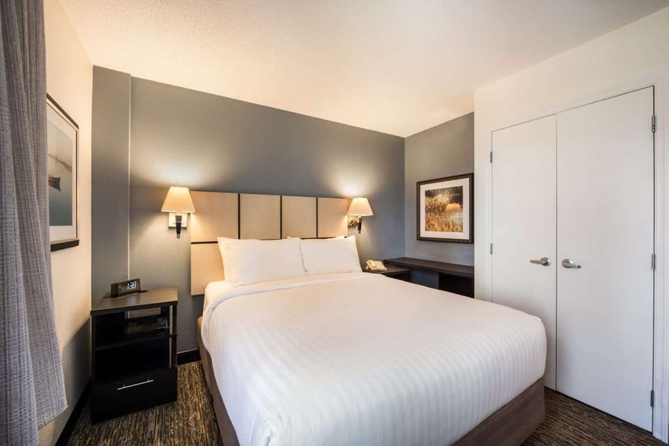 Unwind in crisp linens beneath warm, calming bedside lighting.