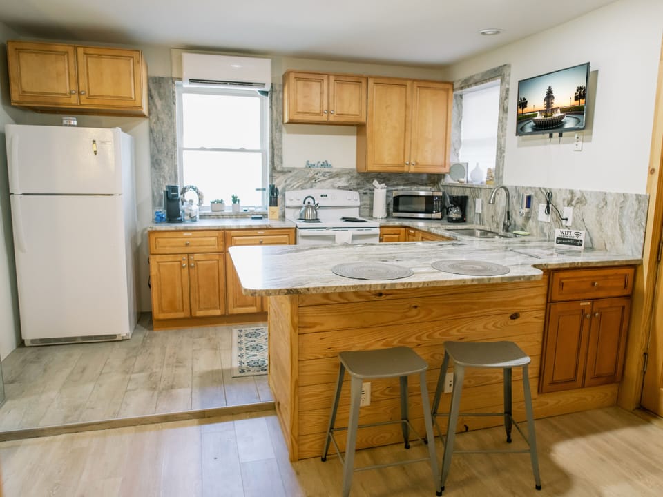 A fully-equipped kitchen with a stove, fridge, and microwave, providing all the essentials for effortless meal preparation and ensuring a comfortable and convenient cooking experience.