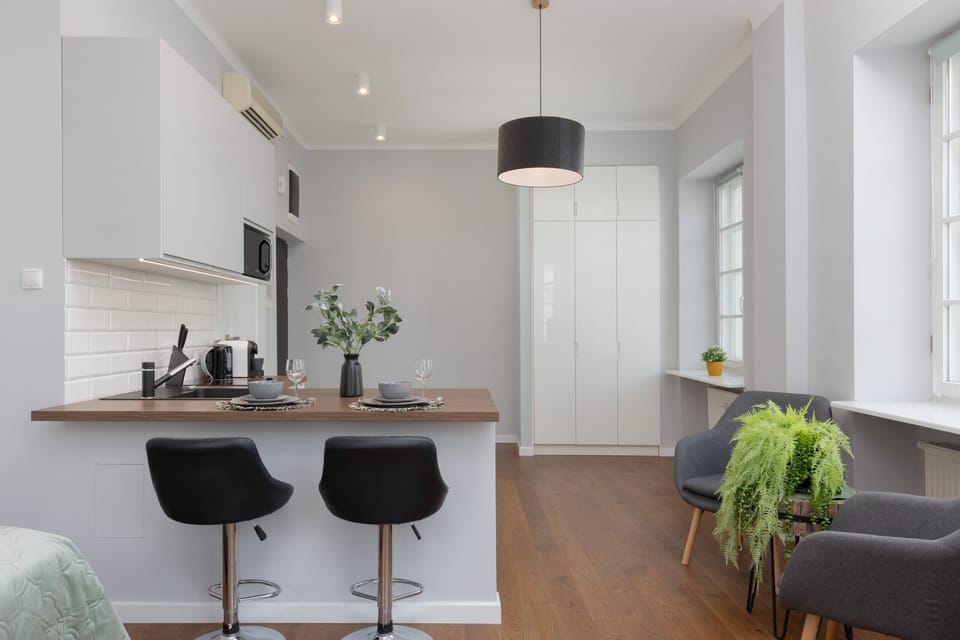The bright white walls and minimalistic kitchen cabinets enhance the sense of space and modernity within the studio.