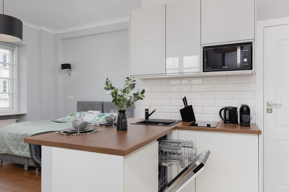 A close-up of the modern kitchen counter showcases its thoughtful design, complete with a coffee maker, kettle, and greenery for a homely touch.
