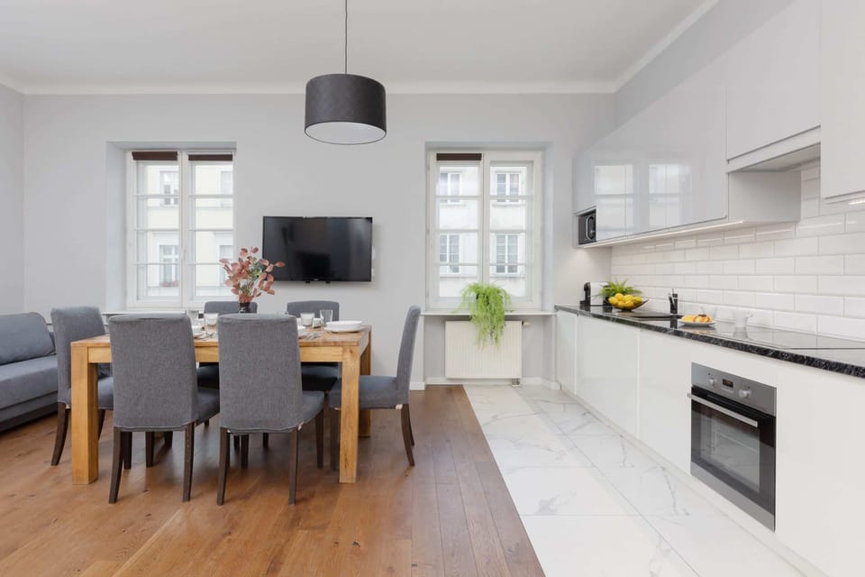 A fully equipped, modern kitchen with white cabinetry, a dark countertop, and a stylish subway tile backsplash.