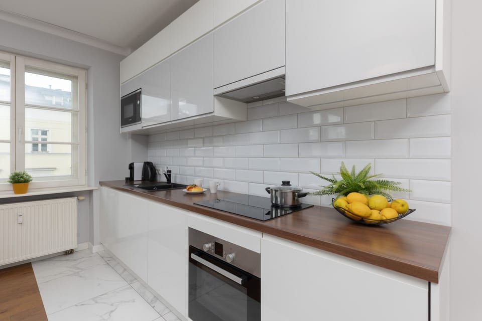 A sleek and modern kitchen with white cabinets, black appliances, and a subway tile backsplash, equipped for all your cooking needs.