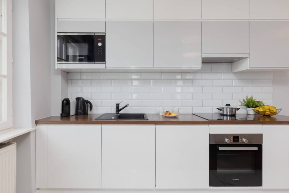 A sleek and modern kitchen with white cabinets, black appliances, and a subway tile backsplash, equipped for all your cooking needs.