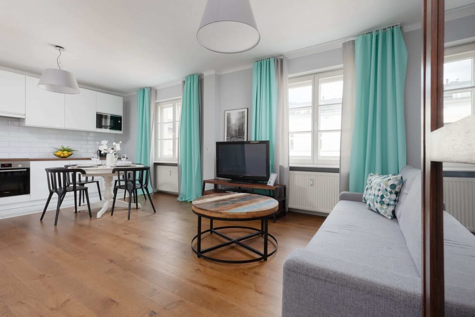 A spacious and bright living area with turquoise accents, a comfortable sofa, a coffee table, and a TV, perfect for relaxation.