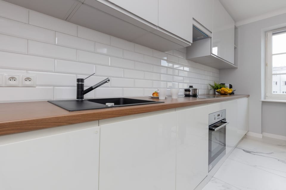 A modern, well-equipped kitchen with white cabinetry, a sleek subway tile backsplash, and wooden countertops.