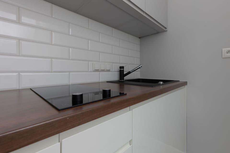 A well-equipped kitchenette with white cabinets, a dark wooden countertop, and a backsplash with white subway tiles.