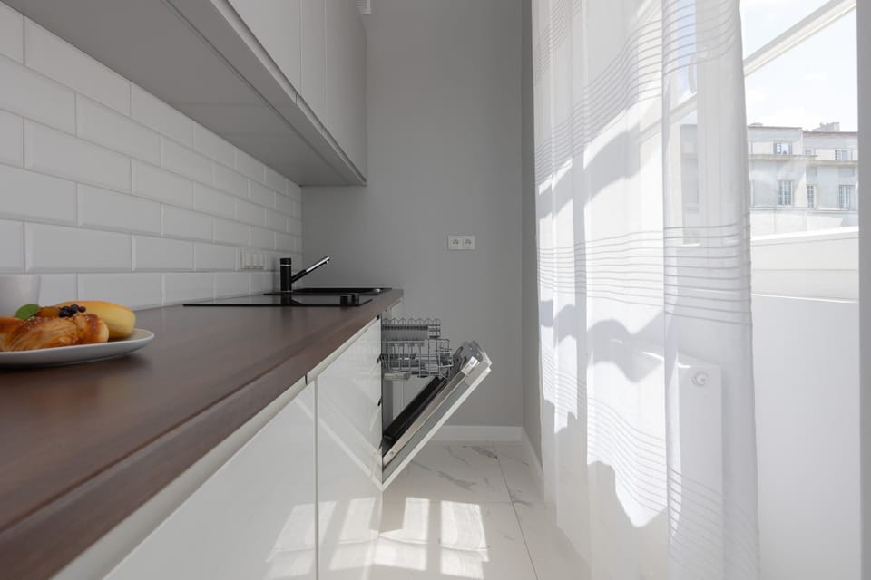 A well-equipped kitchenette with white cabinets, a dark wooden countertop, and a backsplash with white subway tiles.