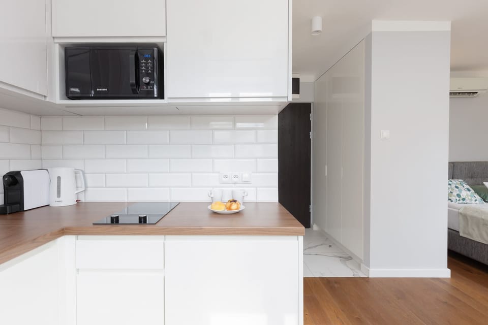 A sleek white kitchen with modern cabinets, black accents, and a functional layout, including a built-in microwave.