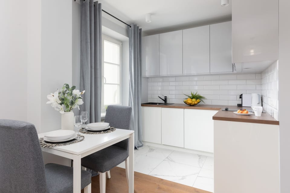 A sleek white kitchen with modern cabinets, black accents, and a functional layout, including a built-in microwave.