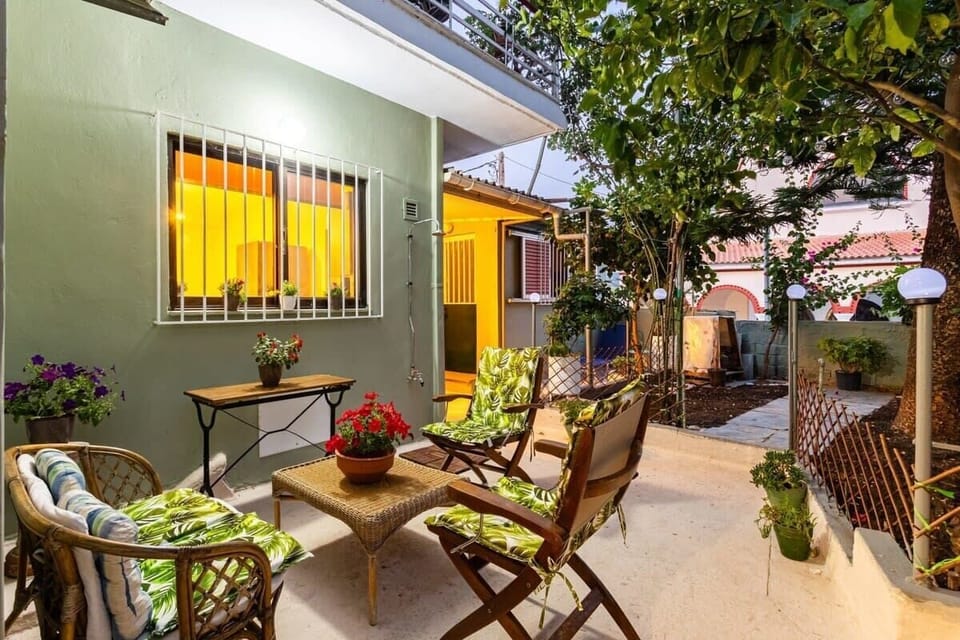 Enjoy a Drink on the Patio under the Olive Tree – A peaceful outdoor setting surrounded by lush greenery, perfect for relaxing moments any time of day.