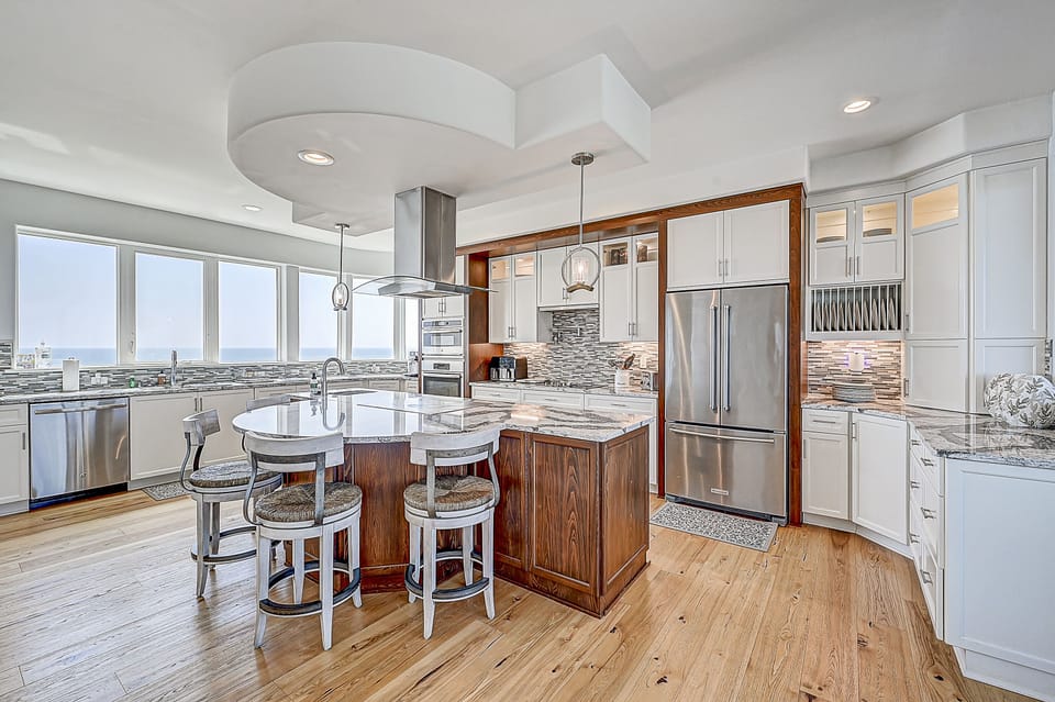 Modern kitchen with a central island, bar stools, and ocean views.