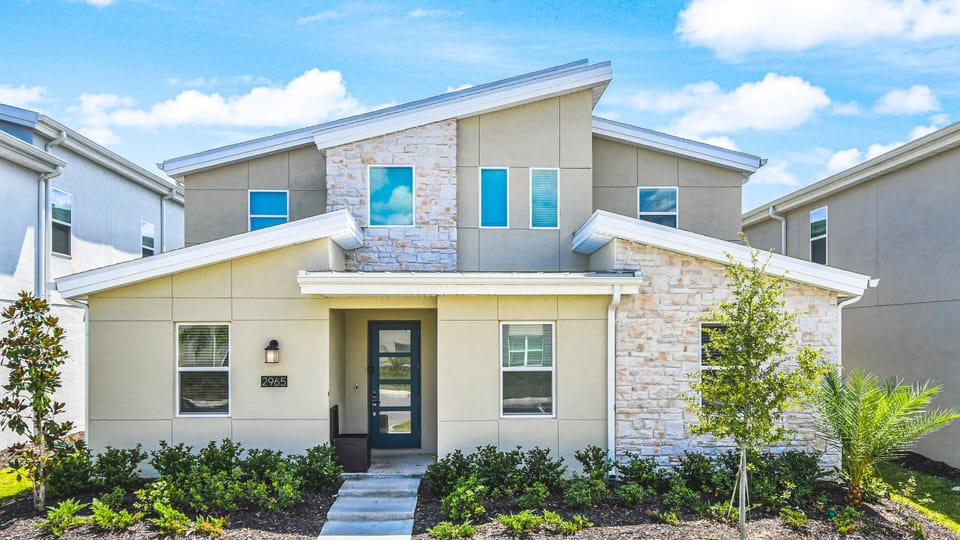 Modern two-story home with a stone-accented façade, sleek windows, and lush landscaping.