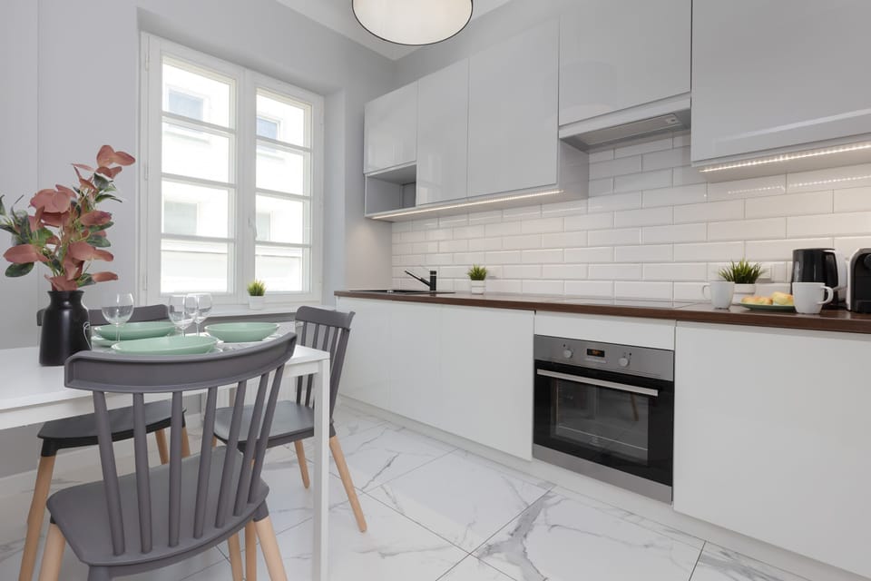 A clean and fully-equipped kitchen area featuring white cabinetry, a tiled backsplash, and wooden countertops.