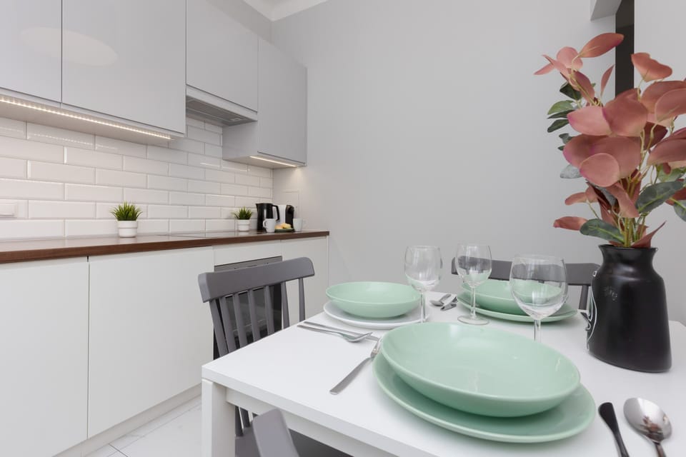A small dining setup with a table, chairs, and a vase with flowers for a homely touch.
