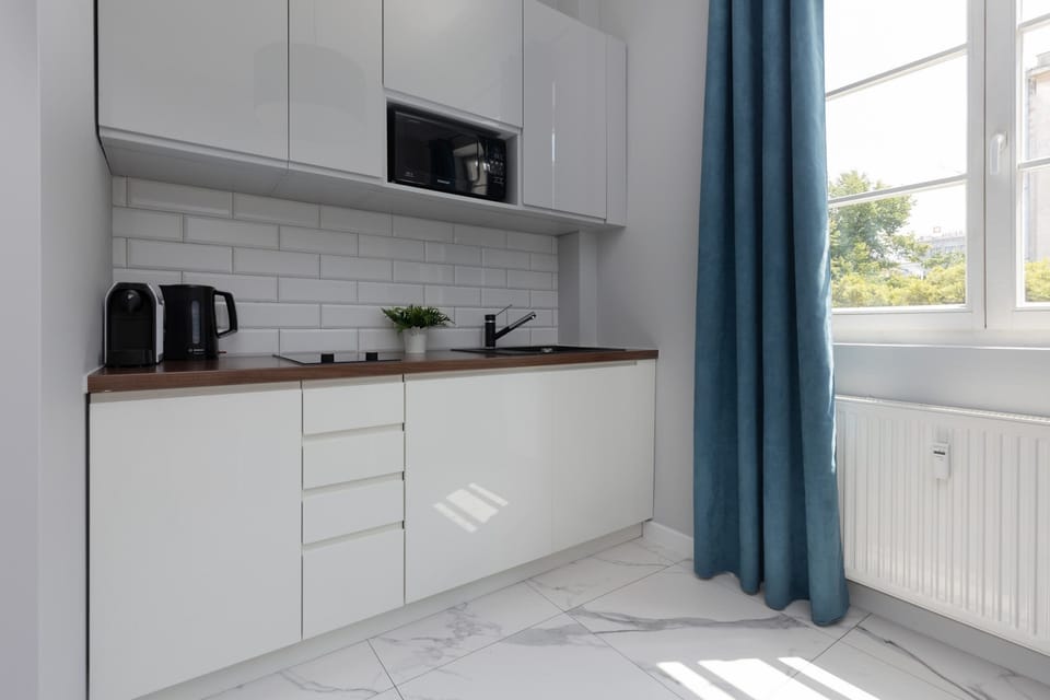 The kitchen area boasts white cabinetry, subway tiles, and modern appliances, offering a sleek and functional cooking space.
