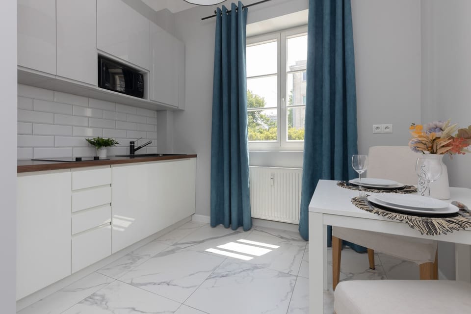 The kitchen area boasts white cabinetry, subway tiles, and modern appliances, offering a sleek and functional cooking space.