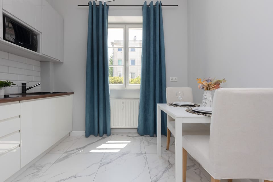 The kitchen area boasts white cabinetry, subway tiles, and modern appliances, offering a sleek and functional cooking space.