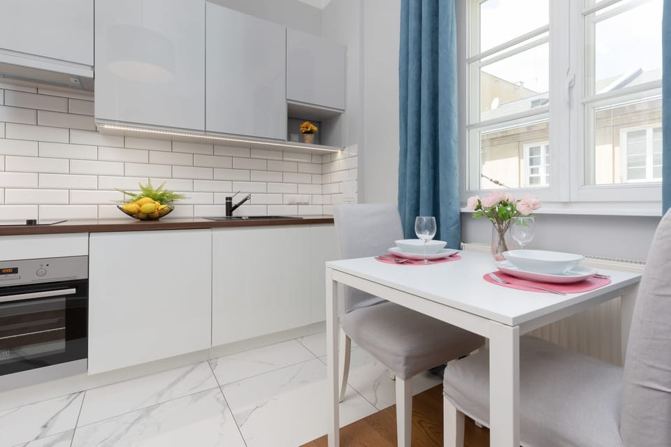 A stylish dining area with a compact table is set with elegant plates and flowers, creating a welcoming atmosphere for meals.