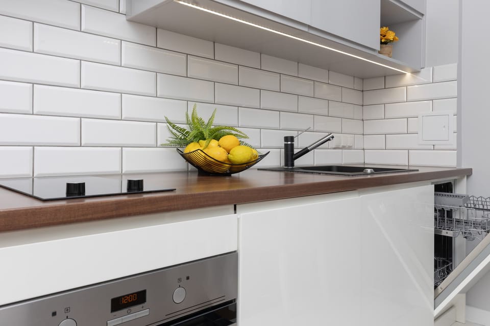 The modern kitchen is equipped with white cabinetry, a subway tile backsplash, and functional appliances, perfect for preparing meals.