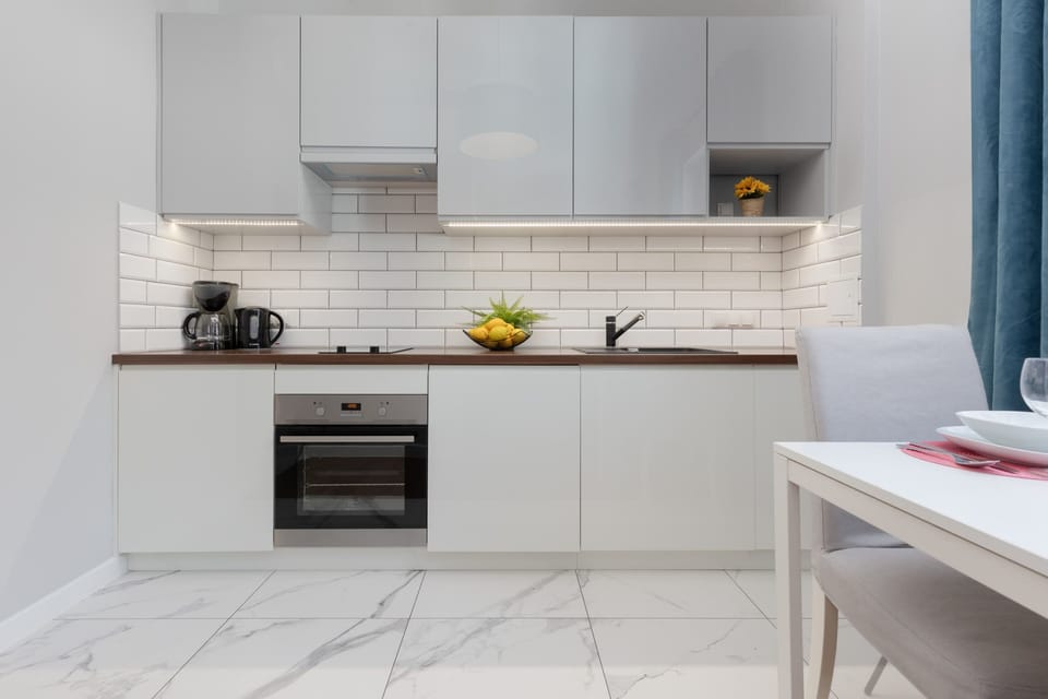 The modern kitchen is equipped with white cabinetry, a subway tile backsplash, and functional appliances, perfect for preparing meals.