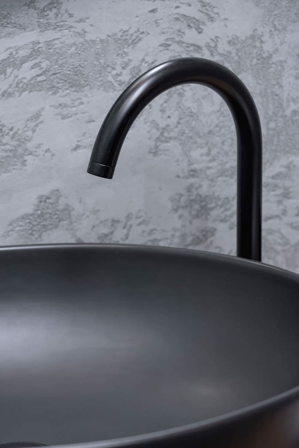 A close-up of a matte black sink faucet, highlighting modern and minimalist design.

