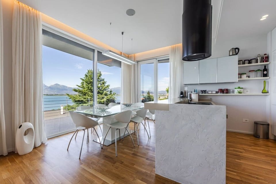 Glass dining table with panoramic Lake Shkodër and Albanian Alps views in this Shirokë villa.