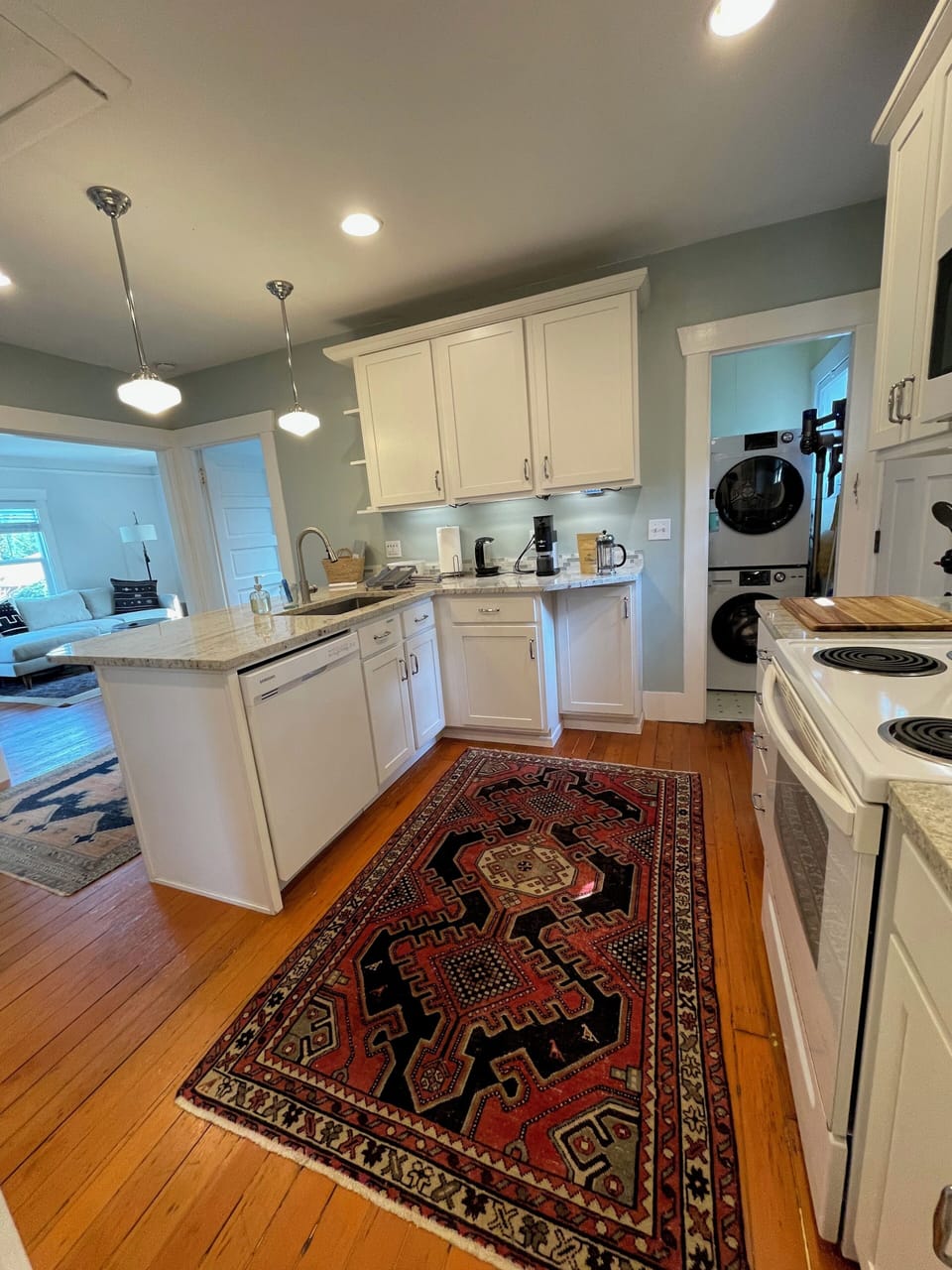 View from kitchen to the living room and laundry area with washer and dryer