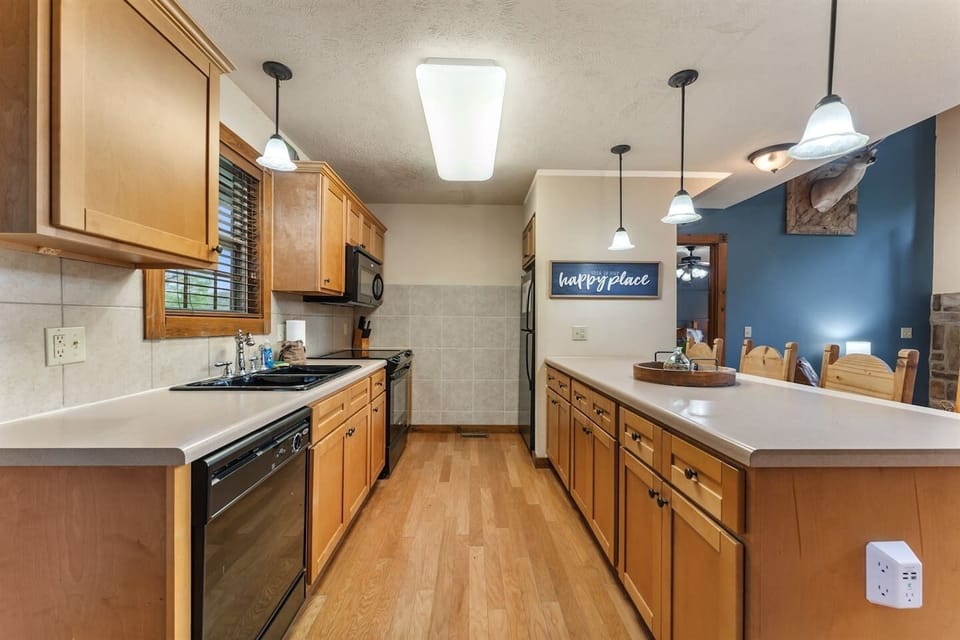 Galley style kitchen with refrigerator, glass top electric range, microwave, and dishwasher.