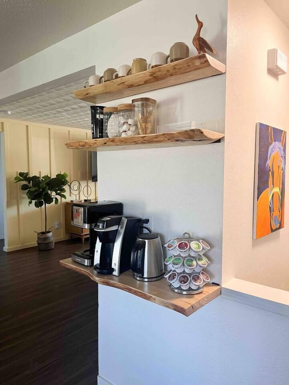 Live edge shelves with coffee pot maker, single serve coffee, coffee bean grinder, electric water kettle, milk frother, coffee filters, stirrers, sugar, half and half, French vanilla cream, hot tea packets, honey sticks.