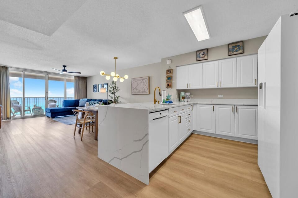 Your spacious kitchen island becomes the heart of coastal living, where morning coffee meets ocean breezes through floor-to-ceiling windows.