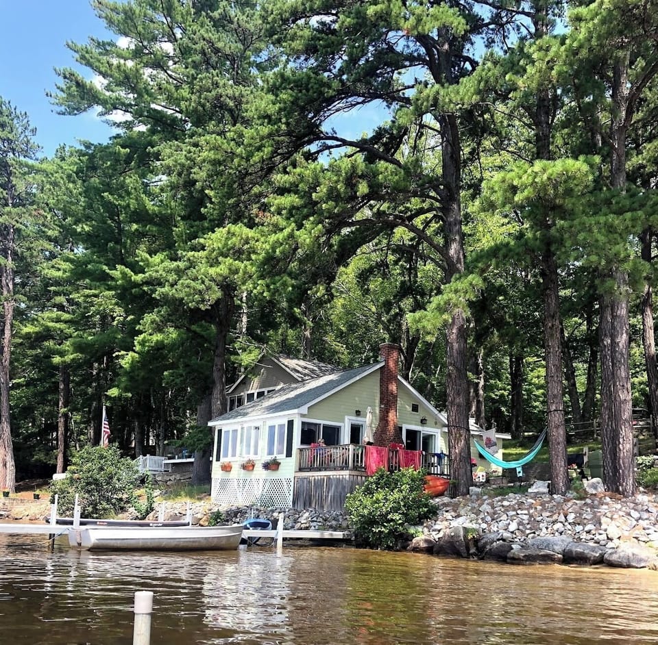 Cottage view from water with private dock, deck and fire pit. 