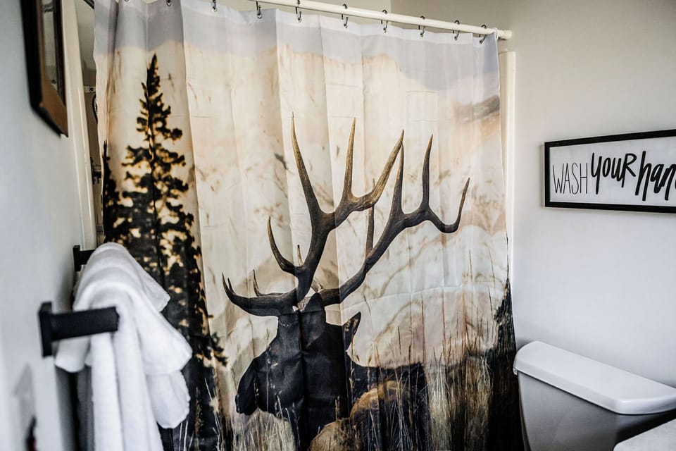 Nature-inspired bathroom with an elk shower curtain and fresh towels.