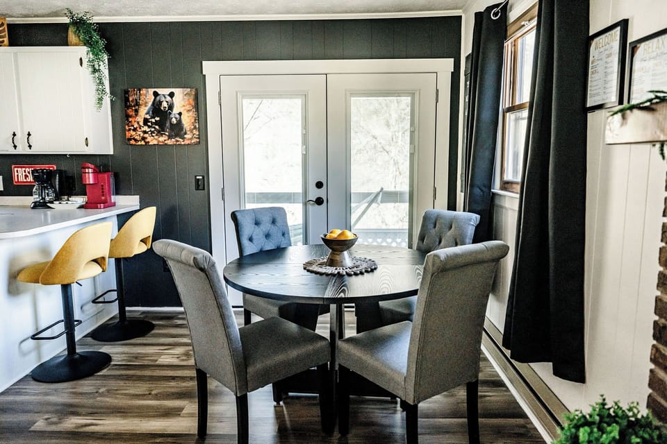 A cozy dining area with a table, comfy chairs, and a view of the outdoors.