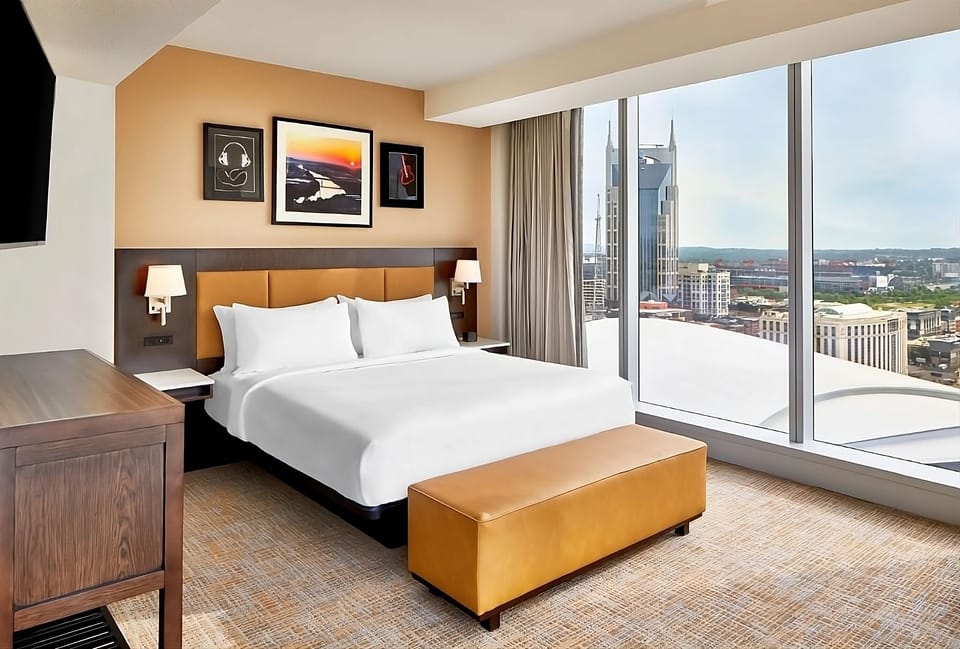 Unwind in a serene king bed beside sweeping city views.