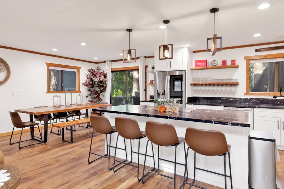 Open-concept dining and kitchen space with large table, modern lighting, and seating for groups. Perfect for shared meals and memorable gatherings.