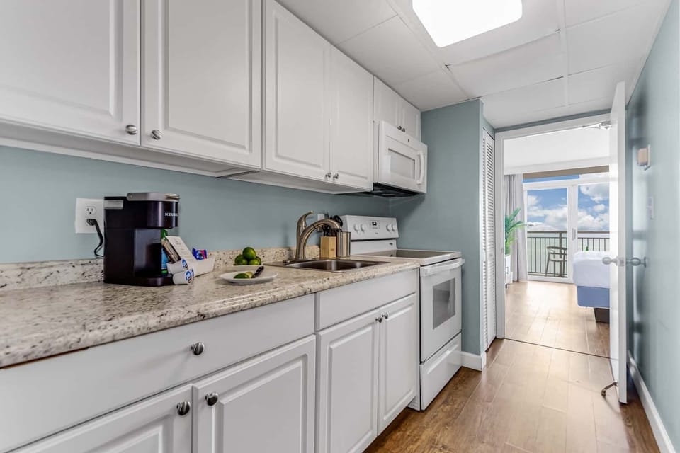 Cook with ease in this fully equipped kitchen featuring modern appliances and sleek countertops. Perfect for preparing your favorite meals while enjoying ocean views in the background.