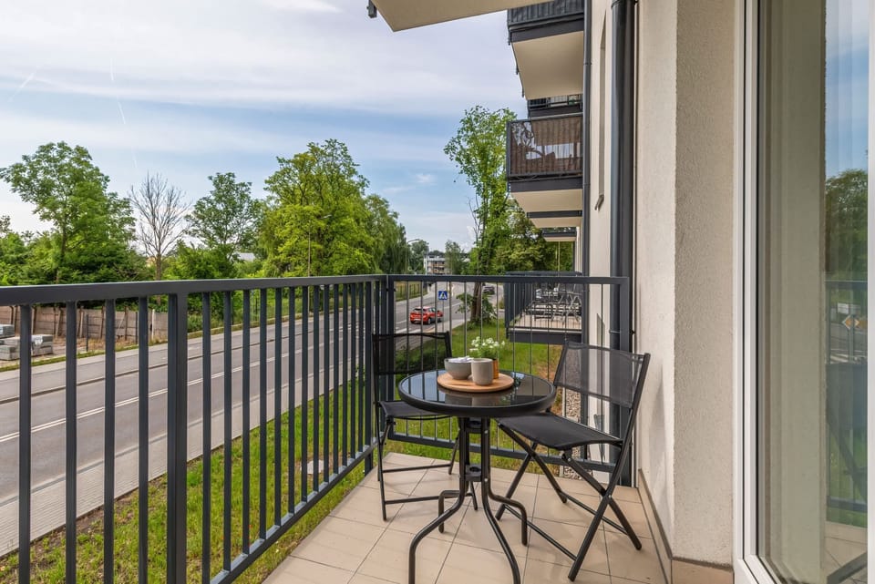 A balcony with a small table and chairs, overlooking greenery for a relaxing outdoor space.

