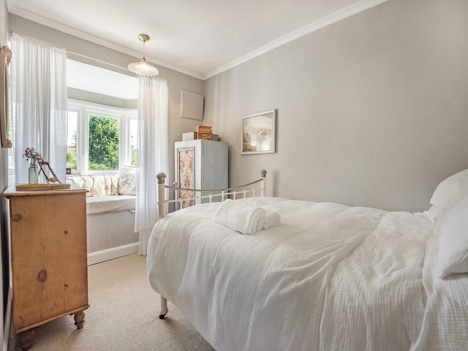 Double bedroom with large cushion filled bay window seat that looks over the garden. It is the perfect &rsquo;Book Nook&rsquo;, but also has a comfortable mattress for a 3rd child to sleep. Bedding on request. | Greenfield Cottage 1866, Worthing