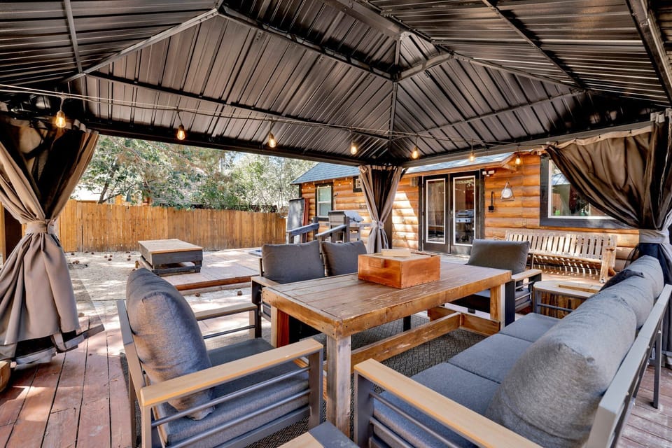 Spacious backyard with a relaxing hot tub, BBQ, outdoor dining area, comfy seating, and charming string lights perfect for peaceful evenings outdoors.