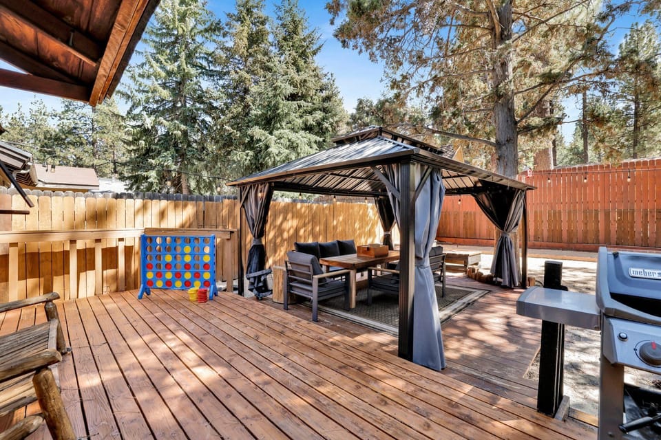 Spacious backyard with a relaxing hot tub, BBQ, outdoor dining area, comfy seating, and charming string lights perfect for peaceful evenings outdoors.