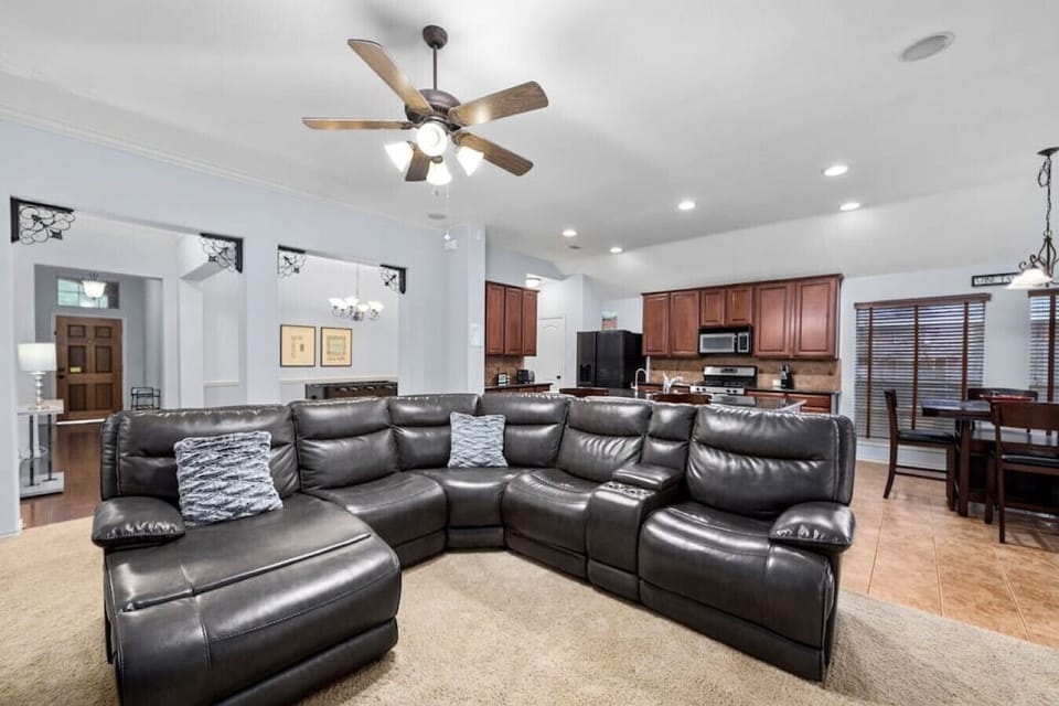 Spacious living room with oversized leather sectional and open sightlines to the kitchen and dining area.