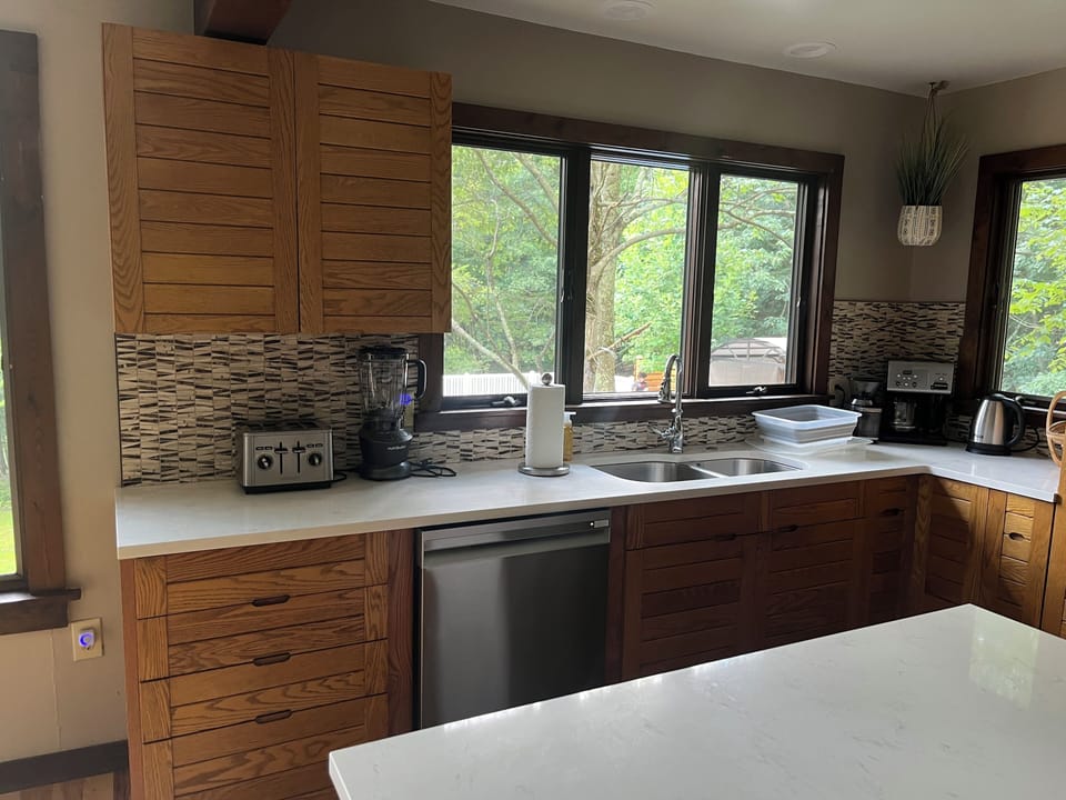 Modern kitchen with a big marble counter and new stainless steel appliances. 