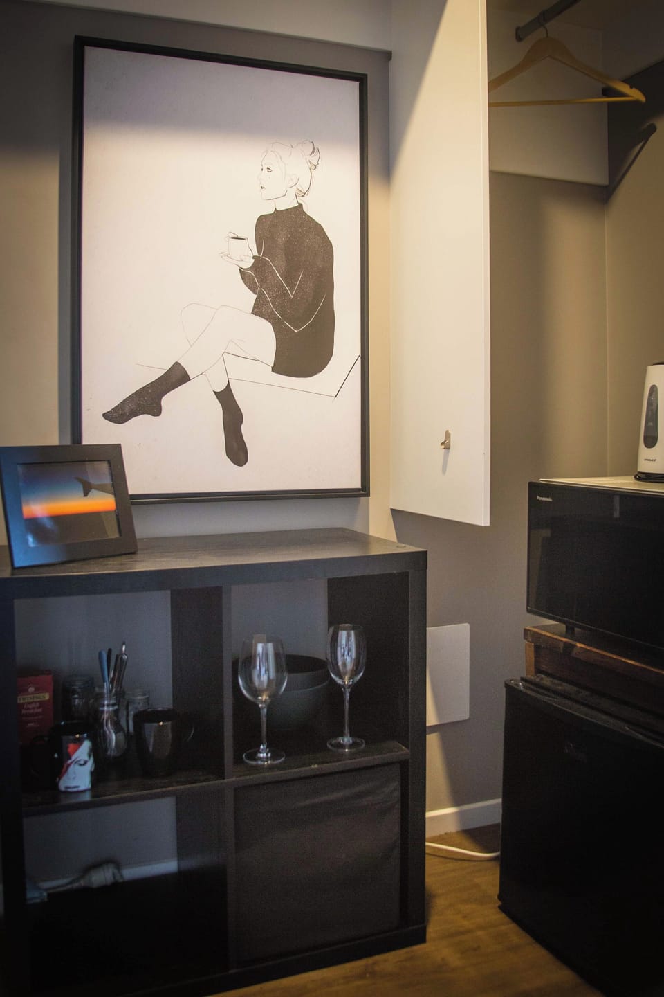 Small kitchenette with microwave, fridge, wine glasses, coffee, and tea.