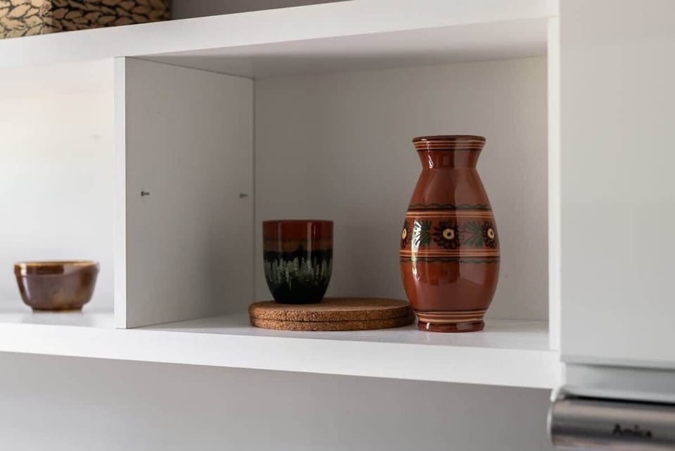 A stylish decorative shelf in the kitchen featuring pottery and simple accents that add a warm touch.

