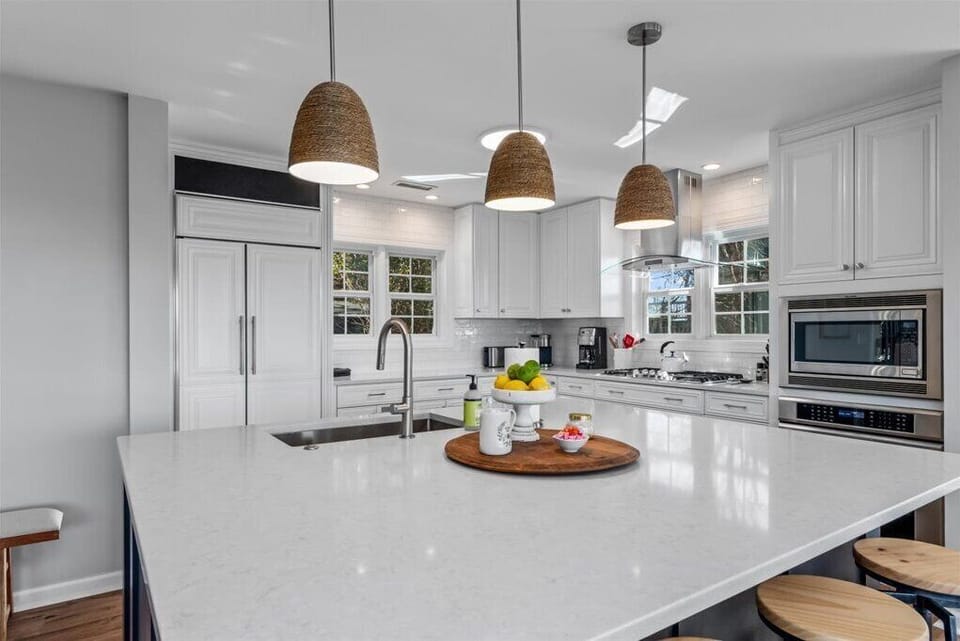Huge quartz island w/ stools is a magnet for guests to gather around & connect