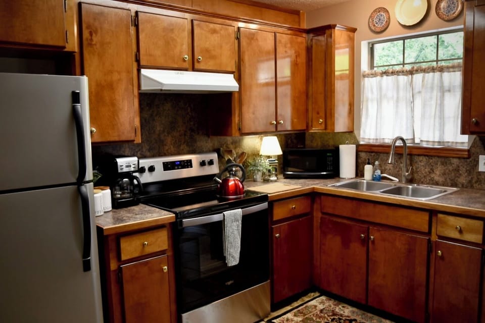 Kitchen with electric stove and fridge. Coffee pot. 
NO dishwasher.