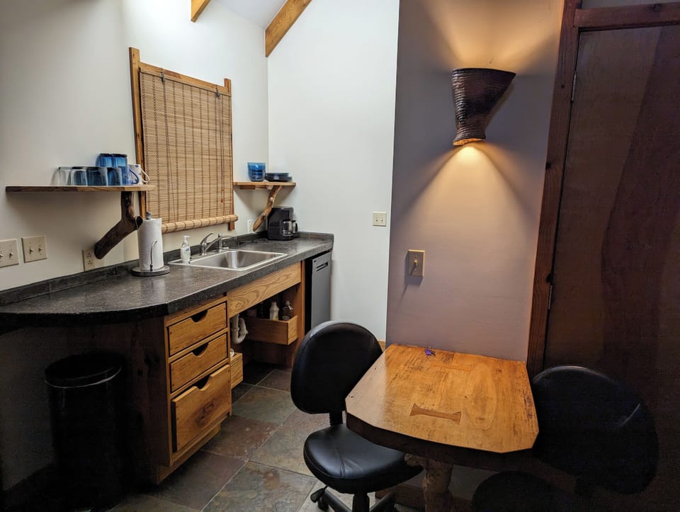 Kitchenette with a cooktop, toaster oven, microwave, fridge, coffee pot & dishes